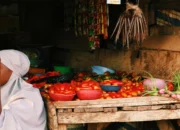 Ilustrasi seorang pedagang bahan pokok menjual hasil pangan di lapak pasar tradisional.